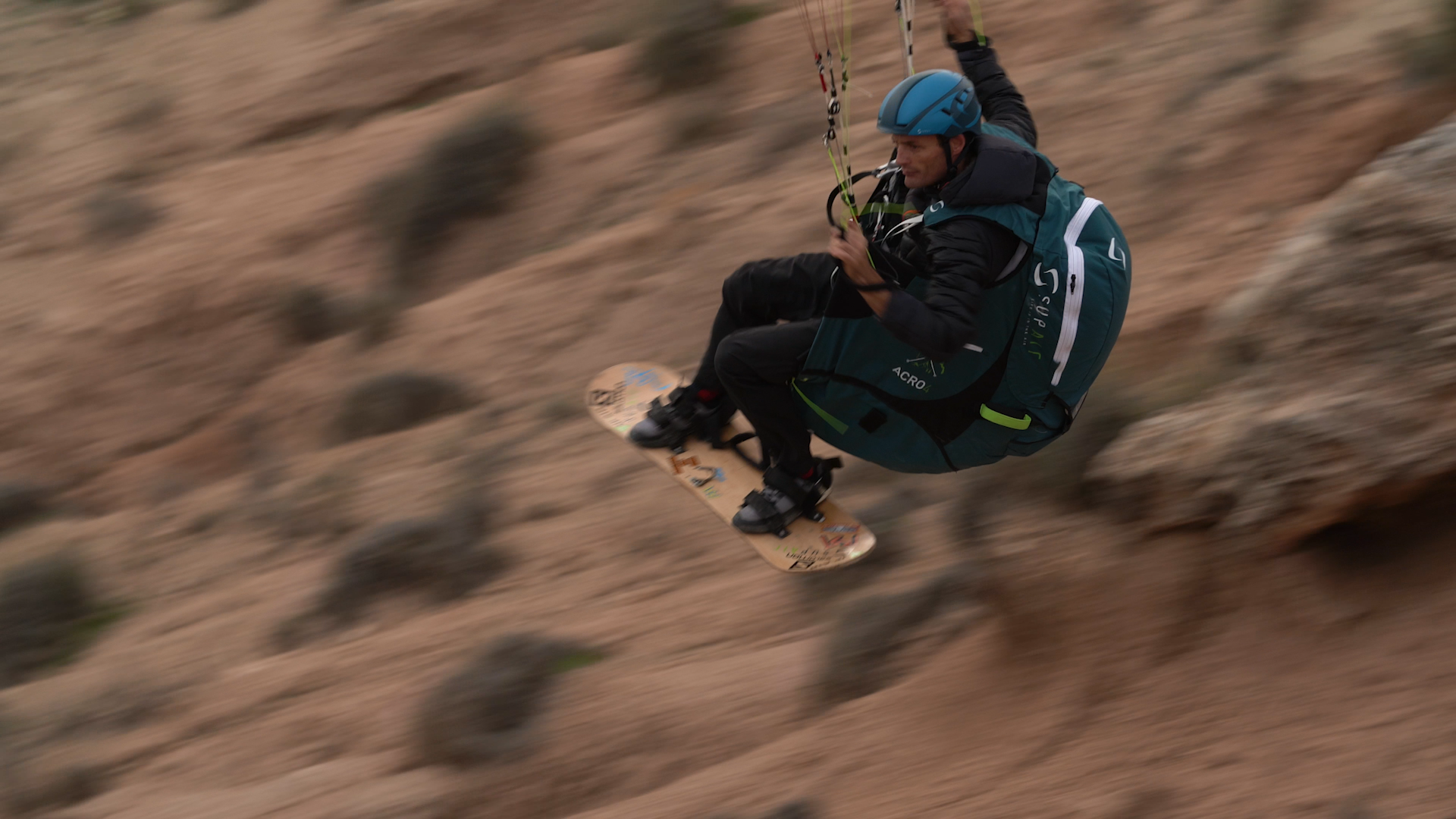 Pilote acro avec sa sellette Acro 4 en ride avec une planche